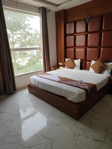 a bedroom with a large bed with a large window at Hotel Shree Amrit Ganga in Haridwār