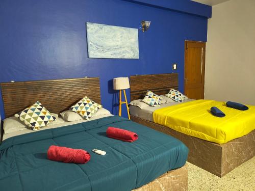 two beds in a room with blue walls and red pillows at Majestic Villa, 5 Bedroom AC in Mysore in Mysore