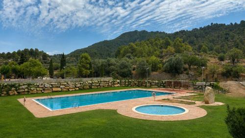 a swimming pool in a yard with a stone wall at Casa rural en Terra Alta con vistas al Tossal d'Engrilló, cerca de la Vía Verde, espacios exteriores, doble barbacoa, ideal para familias, grupos y mascotas in Prat de Compte