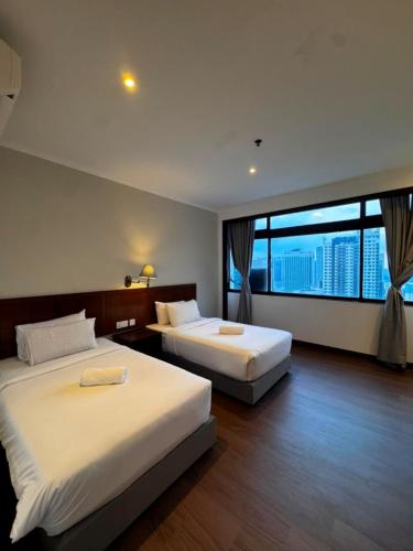 two beds in a hotel room with a large window at Kingston Hotel 21 - JO Hotel Johor Bahru in Johor Bahru