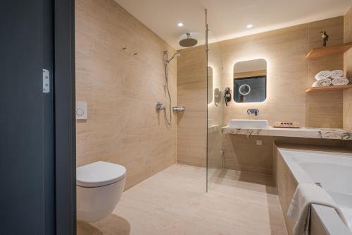 a bathroom with a shower and a toilet and a sink at Van der Valk Hotel Emmen in Nieuw-Amsterdam