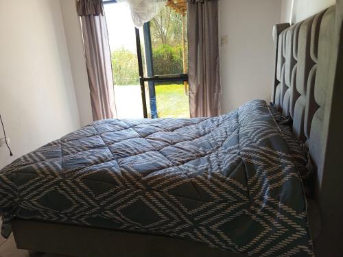 a bedroom with a bed with a quilt and a window at Casa Rústica Diaz in Ica