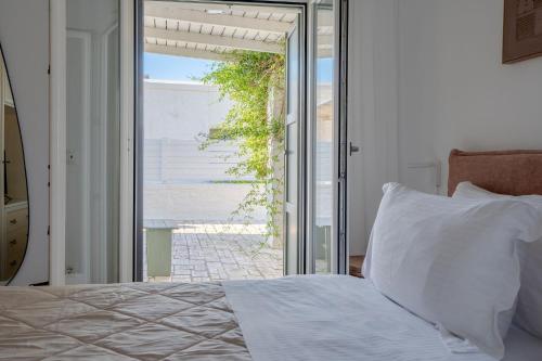 a bedroom with a bed and a sliding glass door at Kriolithos Houses in Parikia