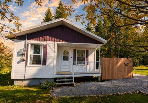 a small white tiny house with a porch at Cozy and Welcoming Chalet with Spa in Saint-Tite-des-Caps
