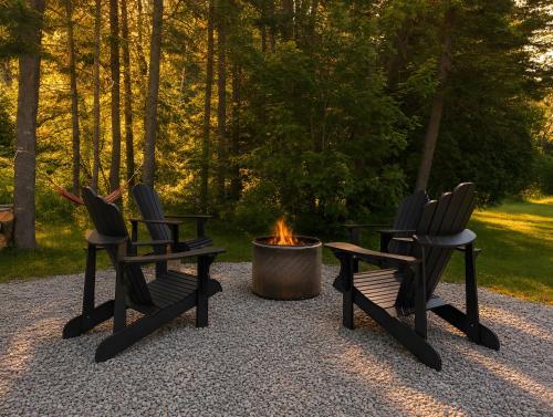 two chairs sitting next to a fire pit at Cozy and Welcoming Chalet with Spa in Saint-Tite-des-Caps