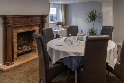 ein Esszimmer mit Tisch und Kamin in der Unterkunft Best Western Claydon Hotel in Ipswich