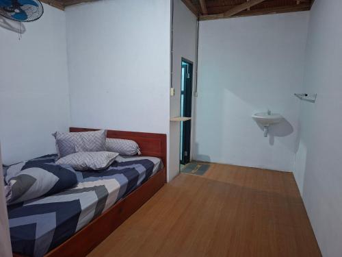 a bedroom with a bed and a wooden floor at Batu Mela Cottage in Banggai