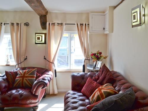 a living room with two leather chairs and a couch at Walnut Cottage in Sproughton
