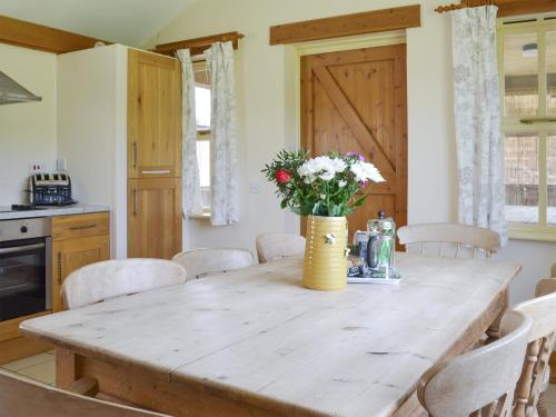 a kitchen with a wooden table with a vase of flowers at Four Bays - Ioh in Brandesburton