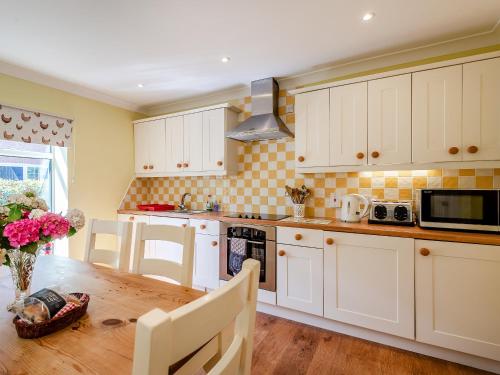 a kitchen with white cabinets and a wooden table at Edlington Hall Cottage in Edlington
