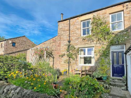 a brick house with a blue door and a garden at Clifford Courtyard in Kirkby Stephen
