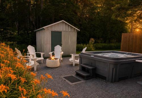 a backyard with a hot tub and chairs and a shed at WOW Chalet Boho - Charlevoix Spa Firepit and BBQ in Saint-Tite-des-Caps