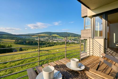 a balcony with a table with two cups on it at Enzian by Mountain ways in Loučná pod Klínovcem