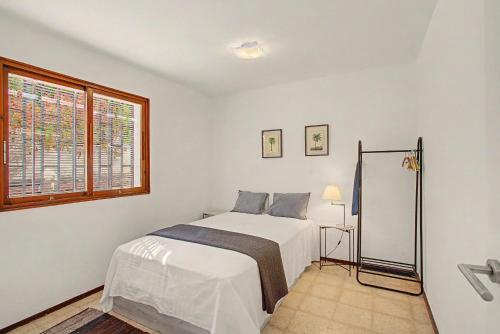 a bedroom with a white bed and a window at A la Playa en San Agustín in Maspalomas