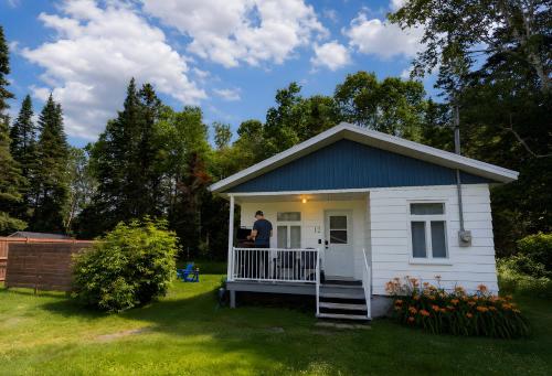 a man standing on the porch of a tiny house at Nature Chalet with Private Spa & Firepit in Saint-Tite-des-Caps