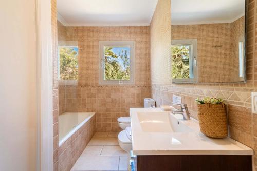 a bathroom with a sink and a tub and a toilet at Villa Casa Blanca Carbo by Sealand Villas in Cala de Sant Vicenc