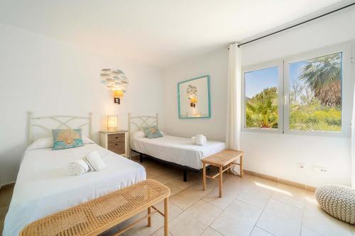 a bedroom with two beds and a window at Villa Casa Blanca Carbo by Sealand Villas in Cala de Sant Vicenc