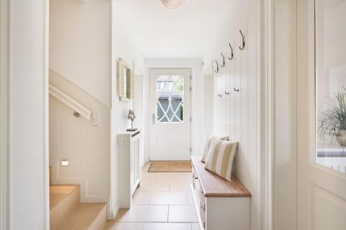 a hallway with white walls and a staircase with a wooden bench at Alt Wrixum Haus 1 in Wrixum