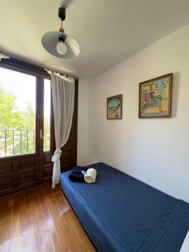 a bedroom with a blue bed and a window at Casa Nectarius in Cifuentes
