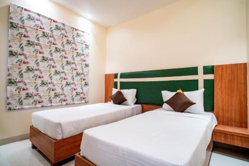 two beds in a room with a painting on the wall at Hotel Avenue 30 in Lucknow