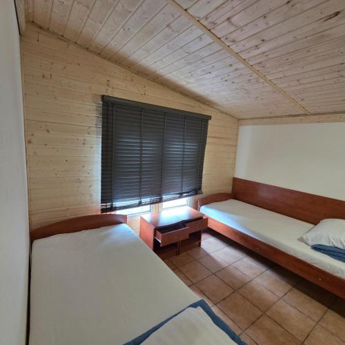 a room with two beds and a window at Rusałka Domki Rodzinne in Rudno