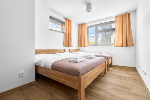 a bedroom with two beds and two windows at Enzian by Mountain ways in Loučná pod Klínovcem