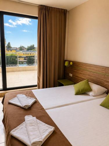 two beds in a hotel room with a window at Deluxe Suites ALL Inclusive in Sunny Beach