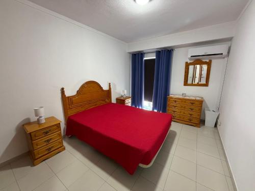 a bedroom with a red bed and a window at Casa Fragata B in Armação de Pêra