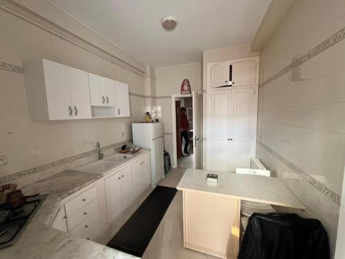 a kitchen with white cabinets and a white refrigerator at Modern Flat , Master Suite , Ain Zaghouan in El Aouina Station
