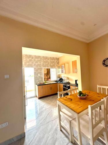 a kitchen and dining room with a wooden table at KMR Apartment - Sira in Sere Kunda