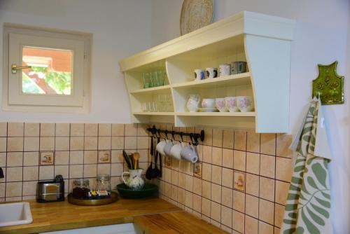 a kitchen with white cabinets and tiles on the wall at Erdei Kisház Sümeg in Sümeg