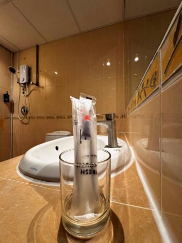 a toothbrush in a glass on a counter in a bathroom at Kingston Hotel 21 - JO Hotel Johor Bahru in Johor Bahru