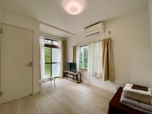 a white room with a television and a window at Guest House TETSU in Oshima
