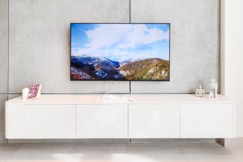 a living room with a tv on a wall at Aurora 1BR - Coastal Chic Luxe Retreat in Abu Dhabi