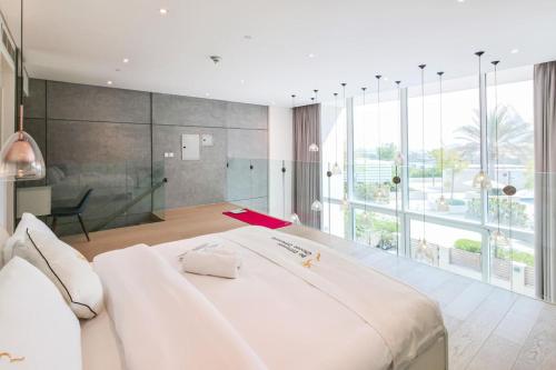 a bedroom with a large white bed and a large window at Aurora 1BR - Coastal Chic Luxe Retreat in Abu Dhabi