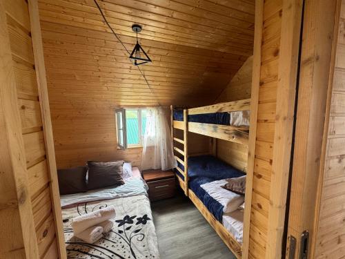 a room with two bunk beds in a wooden cabin at Gomismta Sky House in Gomi