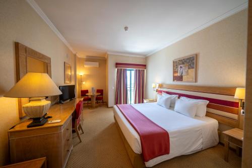 ein Hotelzimmer mit Bett und Fernseher in der Unterkunft Riviera Hotel in Carcavelos