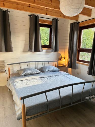 a bedroom with a bed and two windows at MontHuit in Houffalize
