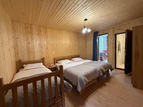 two beds in a room with wooden walls and wood floors at Chalet Gveleti in Barisakho