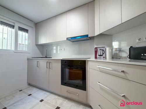 a kitchen with white cabinets and a black oven at Poble Mar 2 in Oropesa del Mar