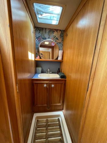 a small bathroom with a sink and a mirror at Bateau Erebus - Bohême chic in Narbonne