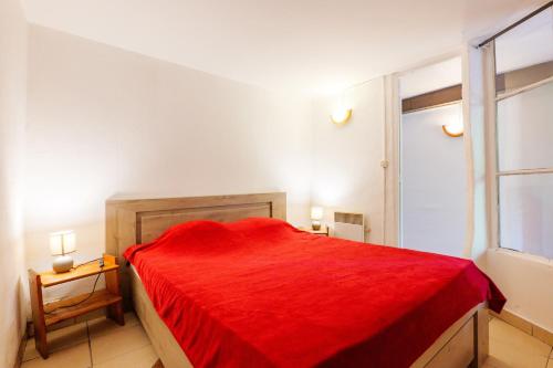 a red bed in a white room with a window at Appartement de charme en Ardèche in Aubenas