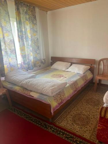 a bed sitting in a room with a window at Guest house Aibek in Kurmenty