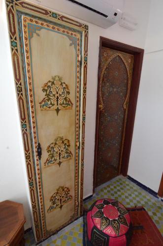 a room with a wall with a door and a bed at Le Cèdre D'argent in Fès