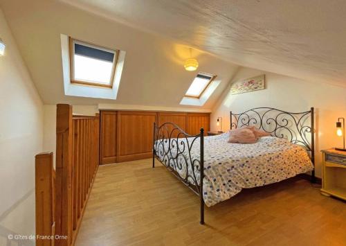 a bedroom with a bed with a metal frame and two windows at L'Érable du perche in Tourouvre