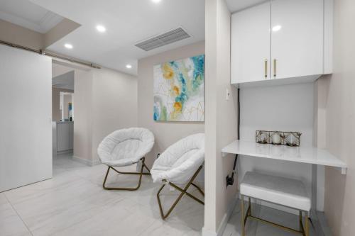 a white kitchen with two chairs and a painting at Designer Oceanview Penthouse & Pool - Condado in San Juan