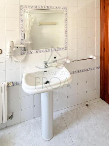 a white sink in a bathroom with a mirror at Xilgar Apto Proa 2d encima de la playa in Raxó