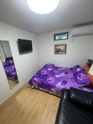 a bedroom with a purple bed and a couch at Tokyo Shinichi House A in Tokyo