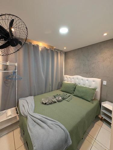 a bedroom with a bed with green sheets and a fan at Pousada - Aconchego da tia Zeni in Mangaratiba