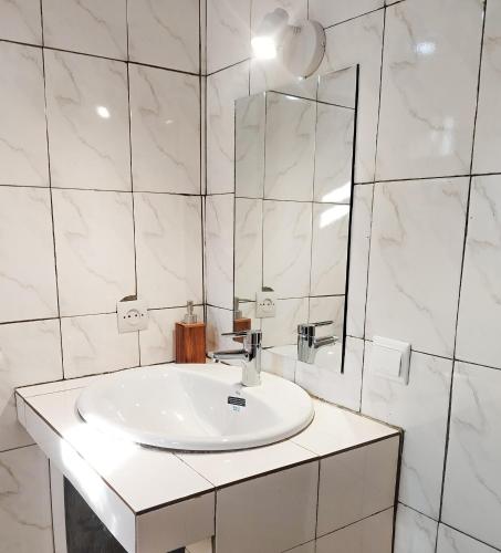 a white bathroom with a sink and a mirror at Les Jardins d'Areca in Antsirabe